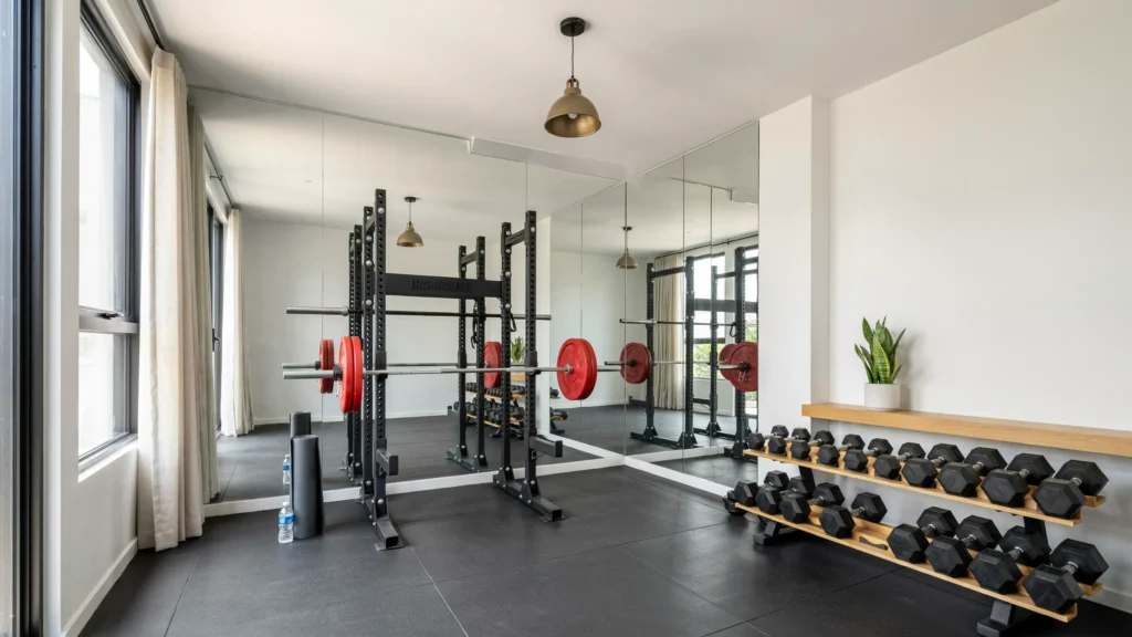 A home gym with wall-to-wall mirrors reflecting and amplifying natural and artificial light, spacious bright atmosphere